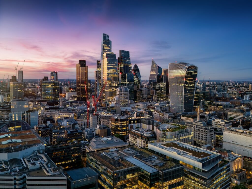 Aerial view of the illuminated skyscrapers at the City of London, England, during evening time with a colourful sky