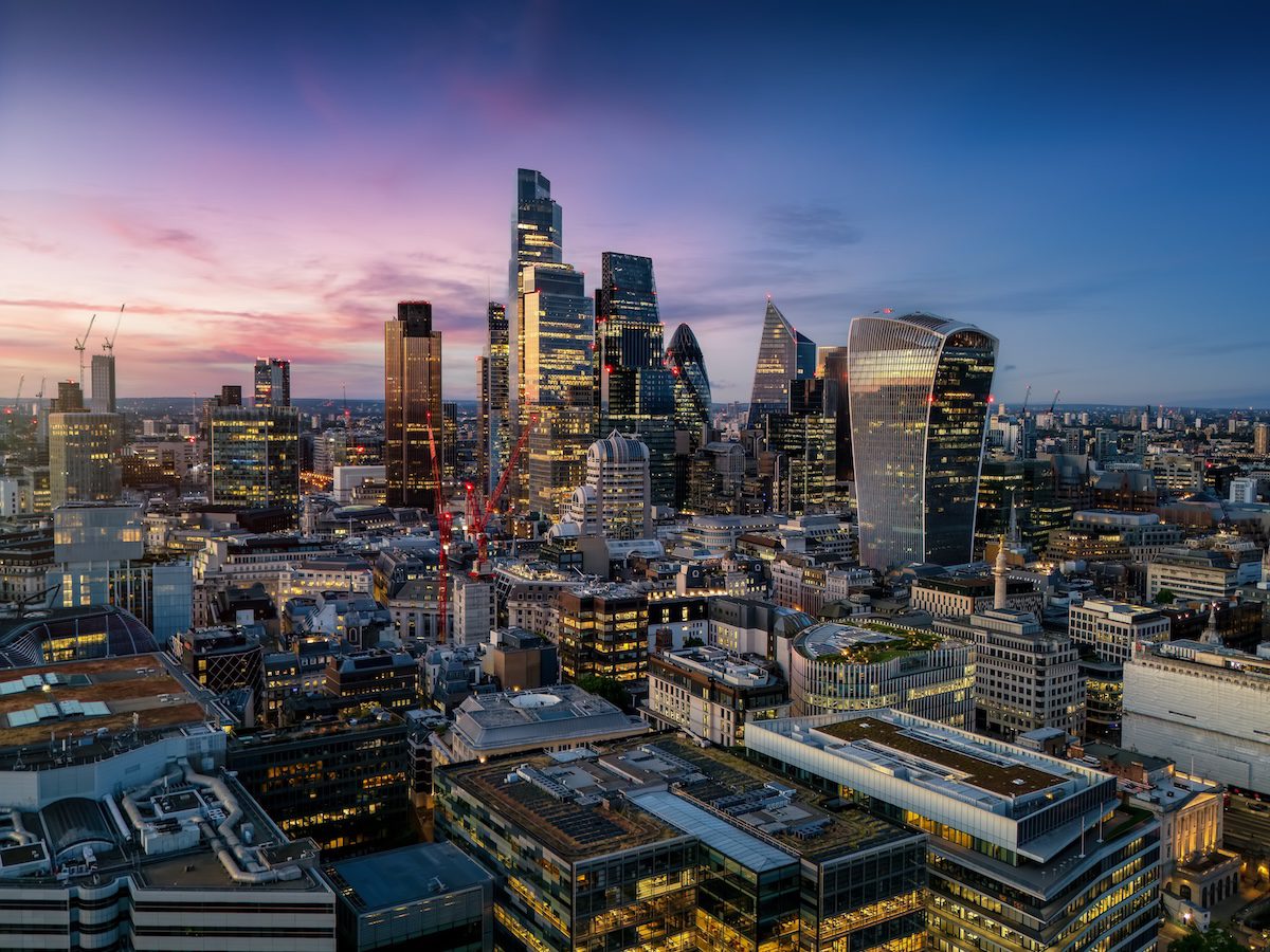 Aerial view of the illuminated skyscrapers at the City of London, England, during evening time with a colourful sky